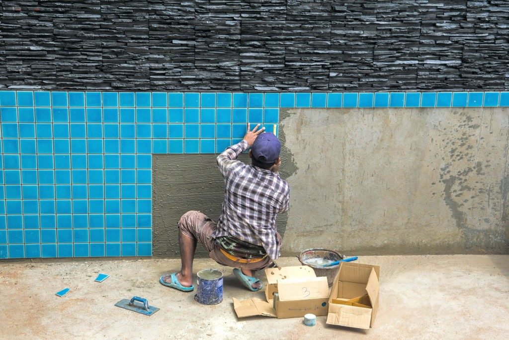 man installing tiles for swiming pool