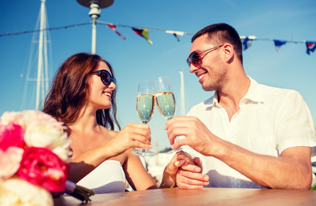 smiling couple wearing sunglasses drinking champagne