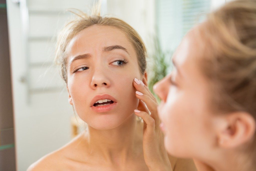 woman looking at her face in the mirror