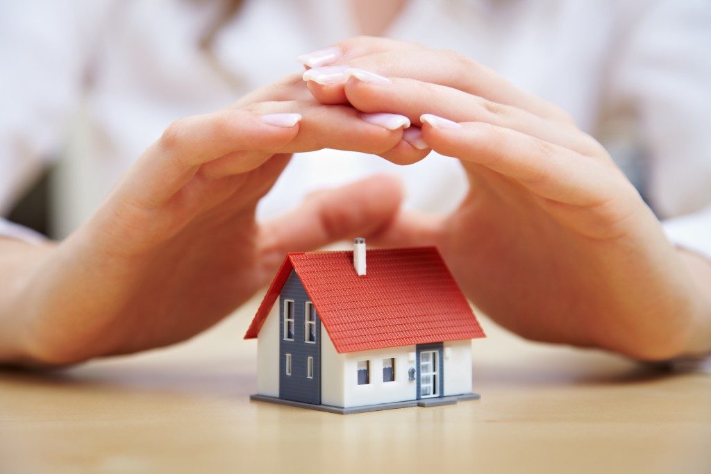 woman's hand over a tiny model of a house