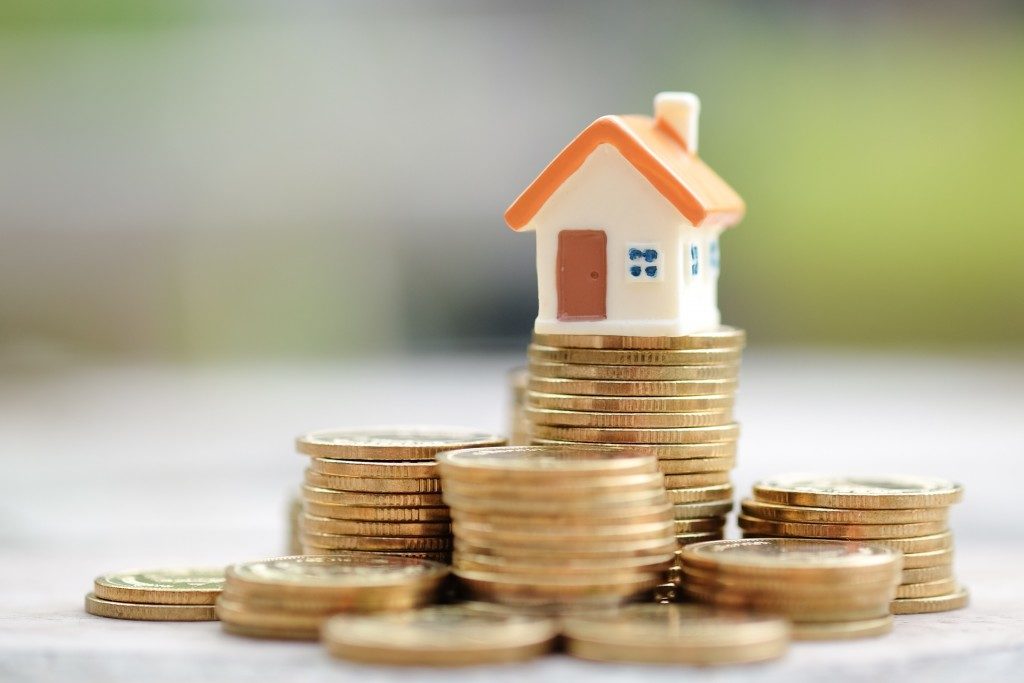 tiny house figure over stacks of coins