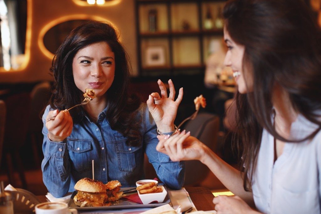 woman enjoying food at the restaurant with her friend